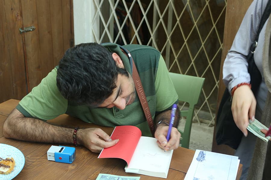 حسام الدین مطهری در حال امضای کتاب در میهمانی دورهمی رمان تذکره اندوهگینان